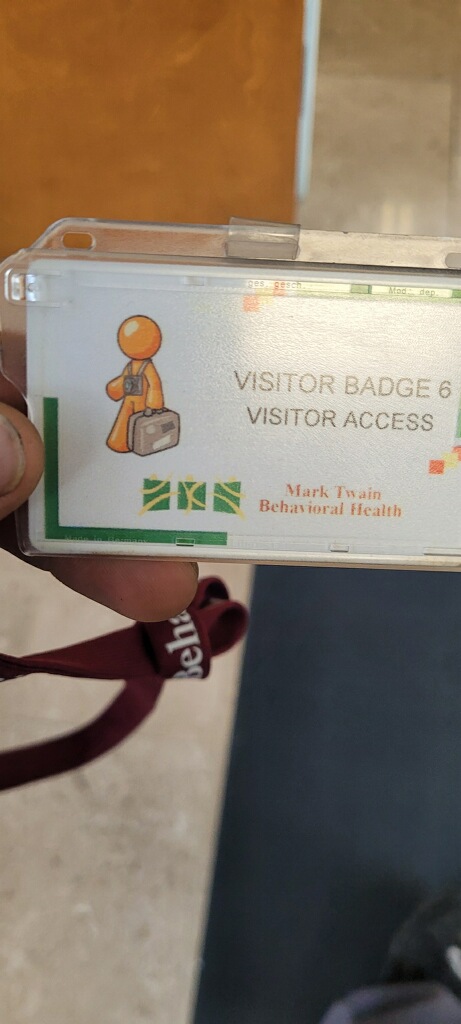 Orange Man carrying a briefcase printed on a visitor badge from Mark Twain Behavioral Health.