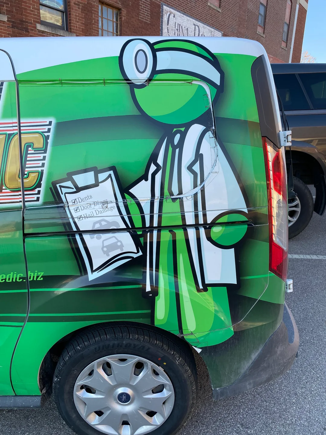 Green mascot graphic on a CarMedic van in Kirksville, Missouri.
